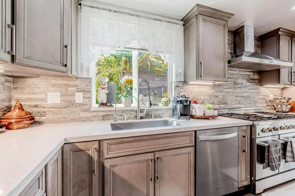 a kitchen with stainless steel appliances granite countertop a sink a stove and a white wooden cabinets
