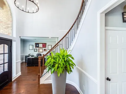 a hallway with wooden floor stairs and furniture