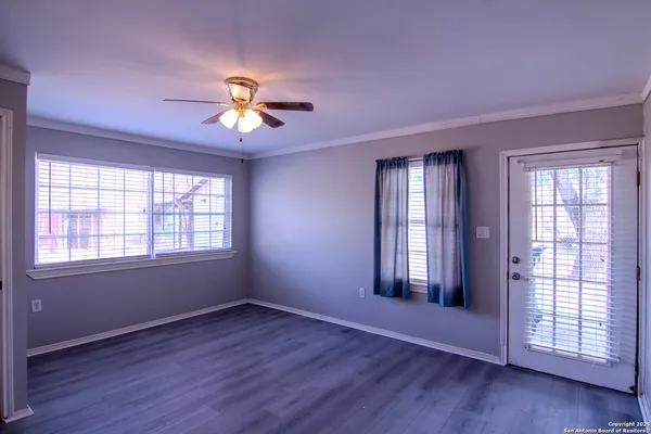 a view of an empty room with a window and wooden floor