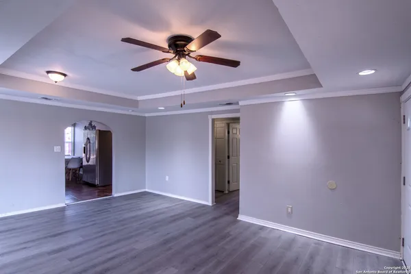 a view of empty room with wooden floor and fan