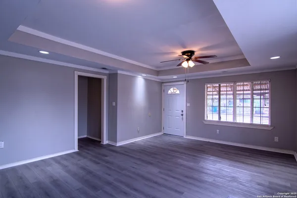 a view of an empty room with wooden floor and a ceiling fan