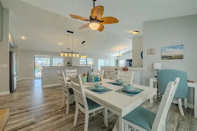 a room with stainless steel appliances kitchen island granite countertop a stove a sink a refrigerator and a wooden floor