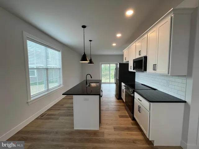 a kitchen with stainless steel appliances granite countertop a sink and a wooden floors
