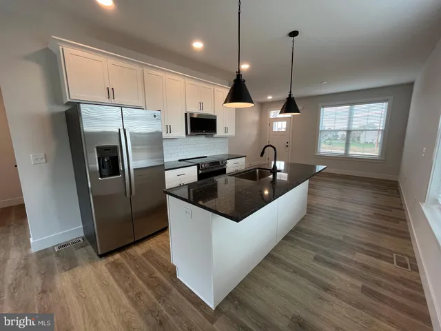 a kitchen with stainless steel appliances granite countertop a sink a refrigerator and wooden floor