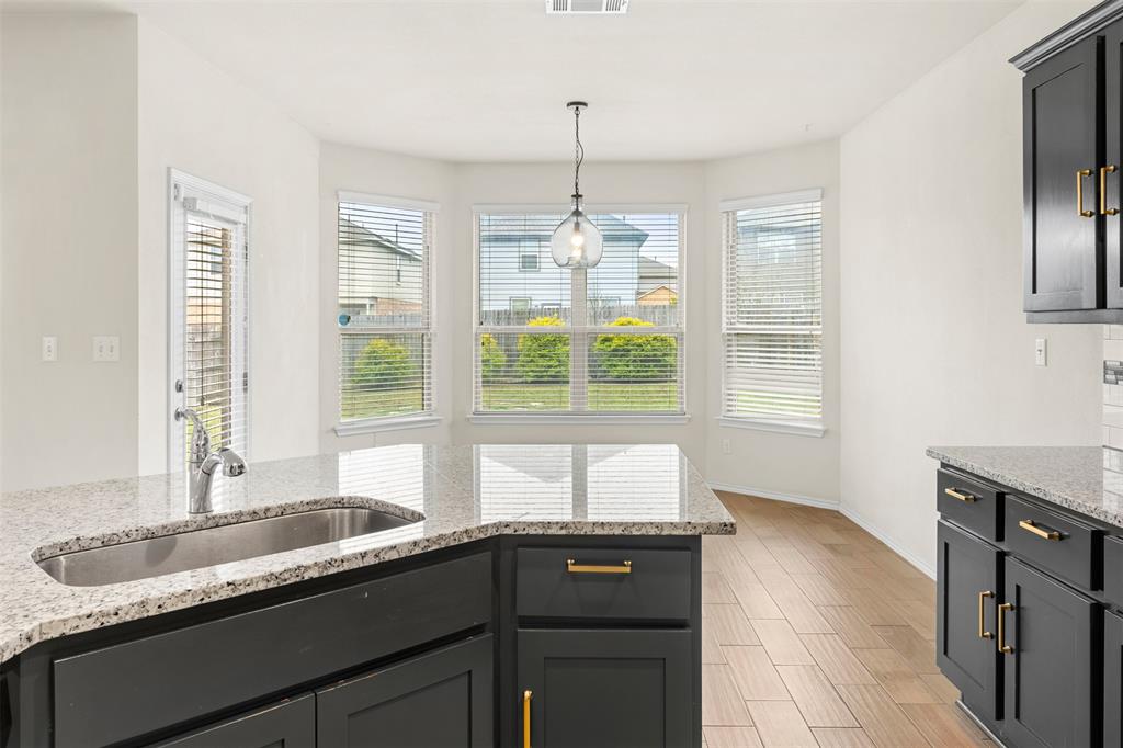 3560 Pauling Loop Round Rock, TX 78665 - Photo 12 of 28 Kitchen featuring light stone countertops, pendant lighting, wood finish floors, and dark cabinetry