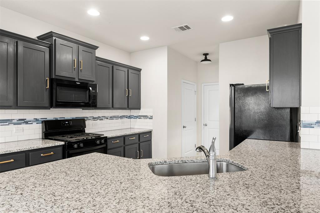 3560 Pauling Loop Round Rock, TX 78665 - Photo 2 of 28 Kitchen featuring black appliances, light stone counters, decorative backsplash, recessed lighting, and dark cabinetry