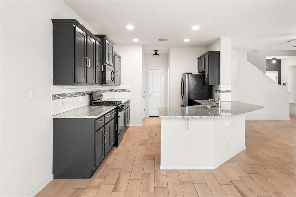 3560 Pauling Loop Round Rock, TX 78665 - Photo 9 of 28 Kitchen featuring stainless steel appliances, dark cabinets, light stone countertops, and recessed lighting