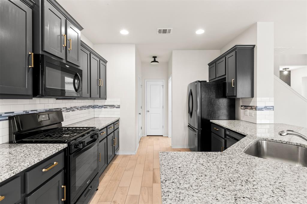 3560 Pauling Loop Round Rock, TX 78665 - Photo 10 of 28 Kitchen featuring black appliances, light stone counters, wood finish floors, tasteful backsplash, and recessed lighting