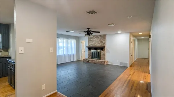 an empty room with wooden floor fireplace and windows
