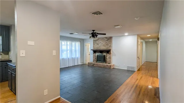 an empty room with wooden floor fireplace and windows