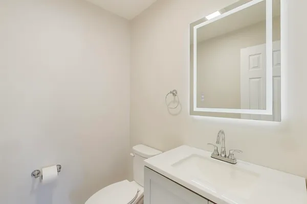 a bathroom with a sink vanity mirror and toilet