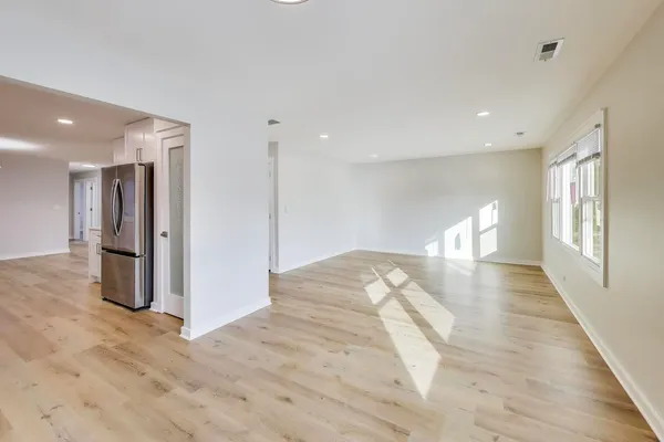 a view of a big room with wooden floor and windows