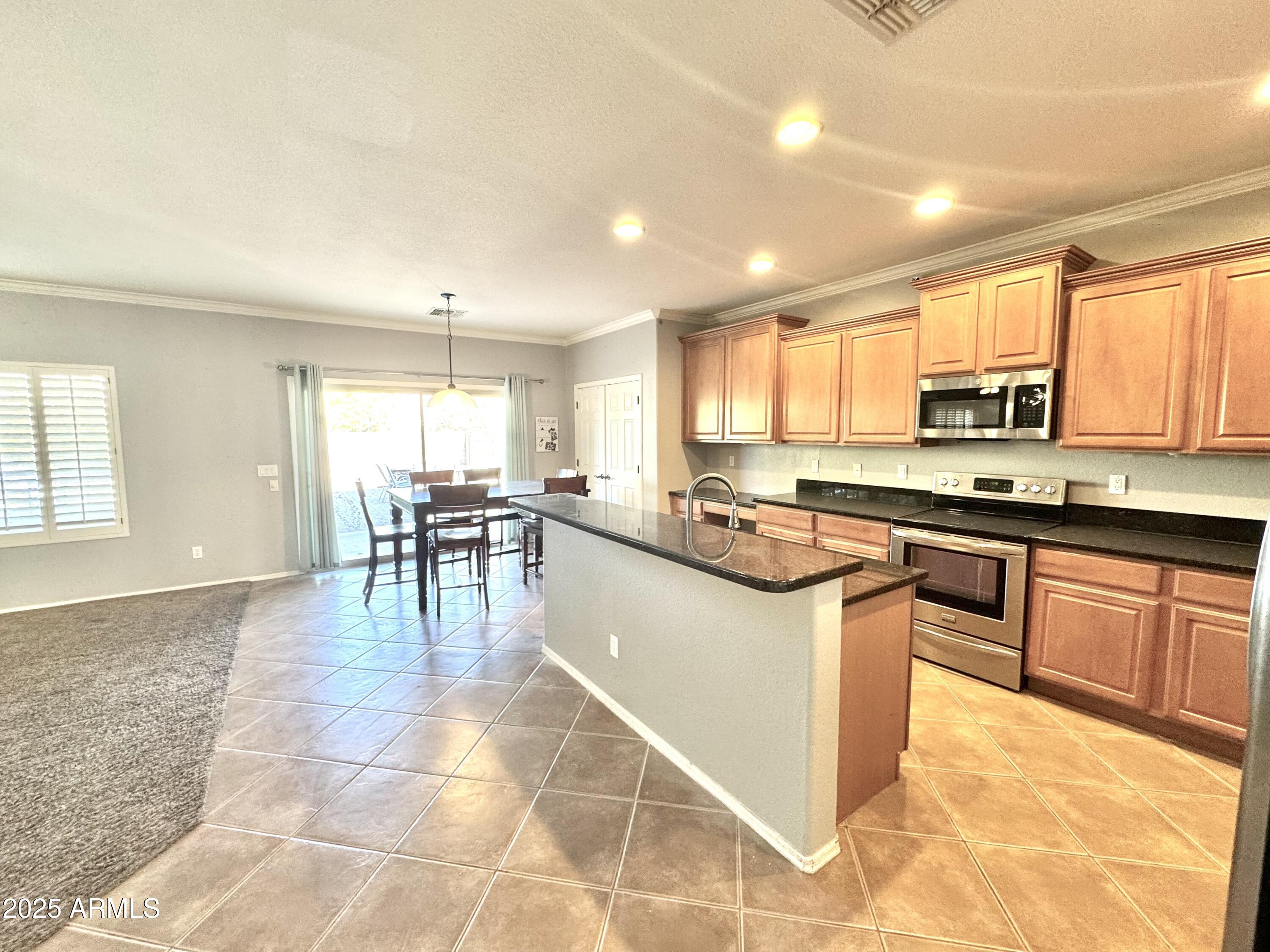 44518 Redrock Road Maricopa, AZ 85139 - Photo 5 of 14 a kitchen with stainless steel appliances granite countertop a stove top oven a sink a dining table and chairs with wooden floor