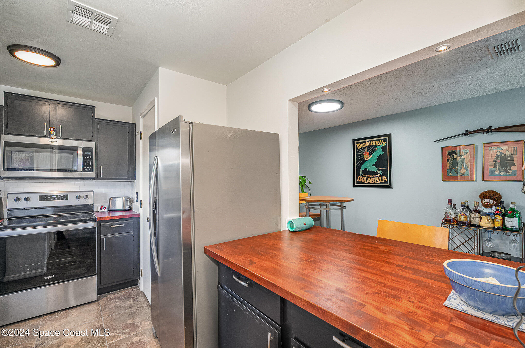 280 Spring Drive, Unit 4 Merritt Island, FL 32953 - Photo 13 of 32 a kitchen with stainless steel appliances kitchen island a table and chairs in it