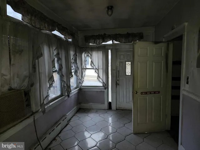 an empty room with wooden floor and kitchen view