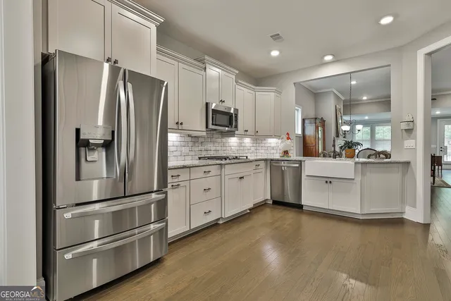 a kitchen with stainless steel appliances white cabinets and wooden floors