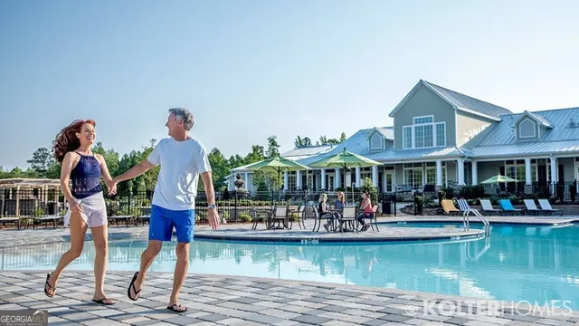 a view of an house with swimming pool lawn chairs and large trees