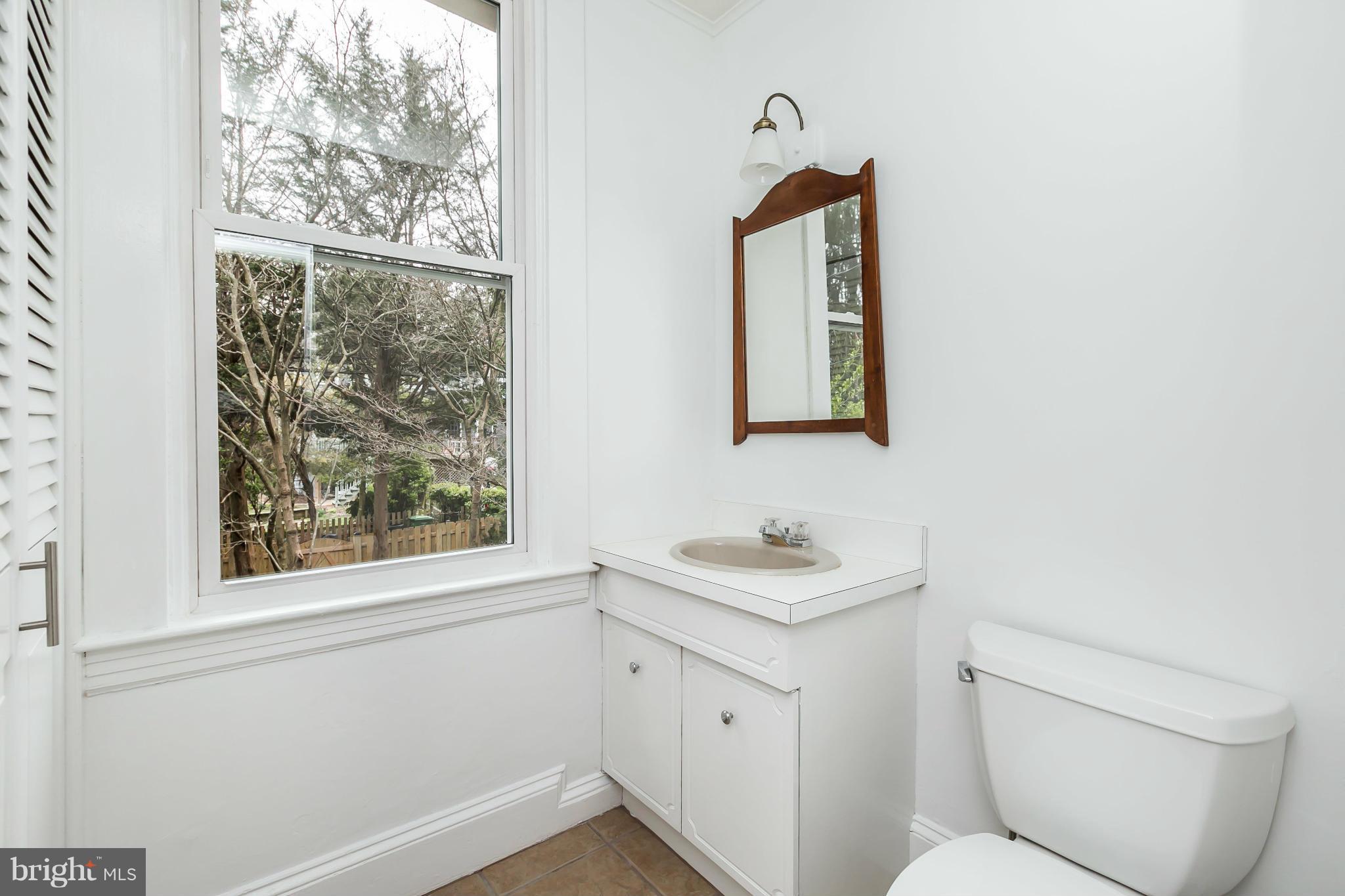 621 Deepdene Road Baltimore, MD 21210 - Photo 13 of 27 a bathroom with a toilet sink and mirror next to a window