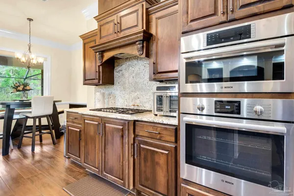 a kitchen with stainless steel appliances granite countertop a refrigerator a oven and a sink with wooden floor