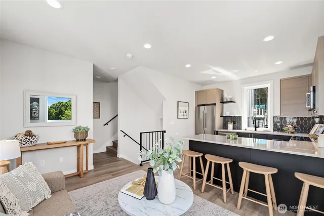 a living room with kitchen island furniture a potted plant and a kitchen view