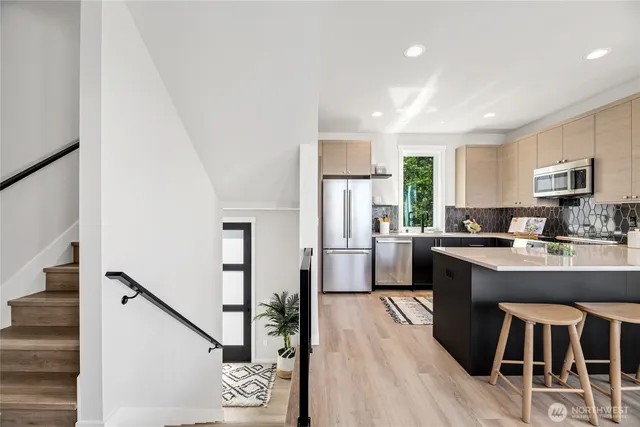 a kitchen with stainless steel appliances granite countertop a refrigerator a stove top oven a sink dishwasher and white cabinets with wooden floor