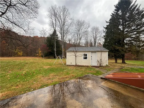 a view of a house with a yard and large tree