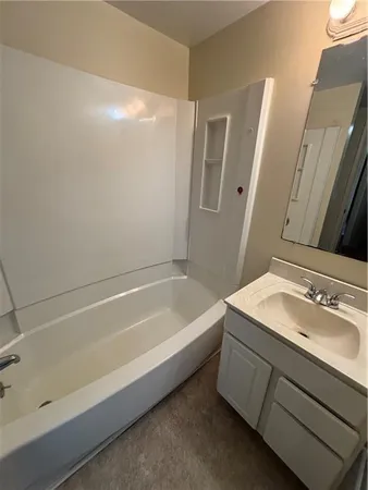 a bathroom with a tub sink and mirror