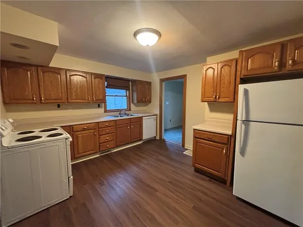 a kitchen with stainless steel appliances granite countertop a refrigerator a stove top oven and wooden floors