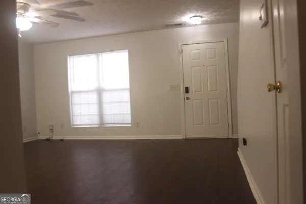 an empty room with wooden floor and windows with curtains