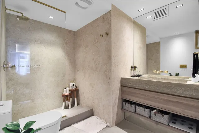 a bathroom with a granite countertop sink a toilet and shower