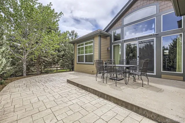 a patio with table and chairs and potted plants