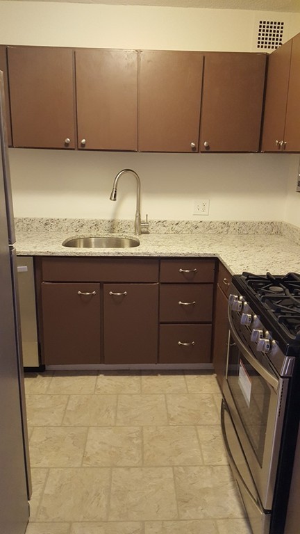 33 Pond Avenue, Unit 902 Brookline, MA 02445 - Photo 4 of 17 a kitchen with granite countertop a cabinets and a stove top oven