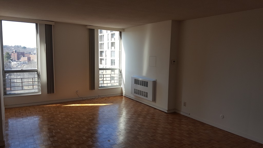 33 Pond Avenue, Unit 902 Brookline, MA 02445 - Photo 8 of 17 an empty room with wooden floor and windows