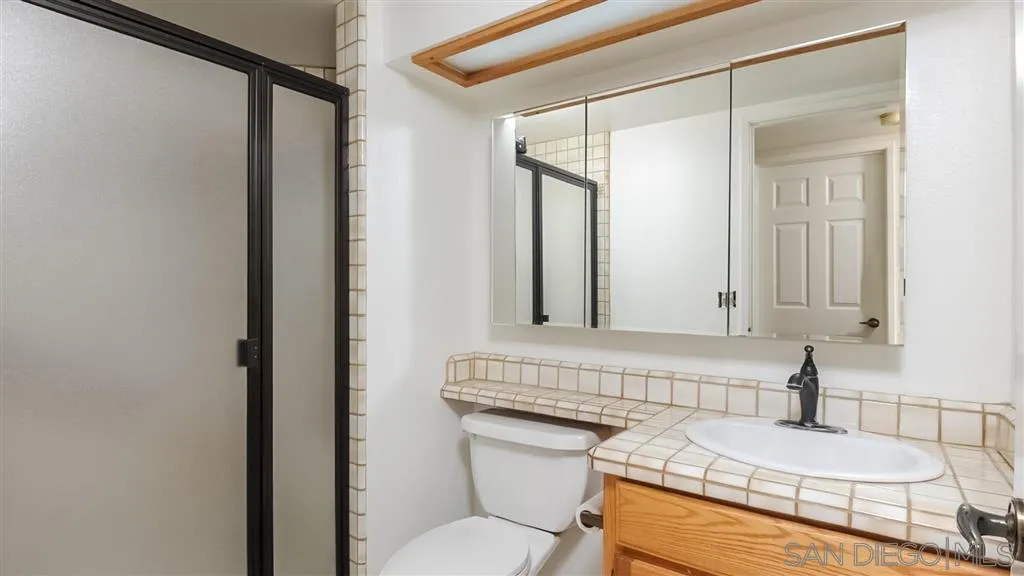 14662 Silverset Street Poway, CA 92064 - Photo 13 of 25 a bathroom with a granite countertop sink a mirror and a shower