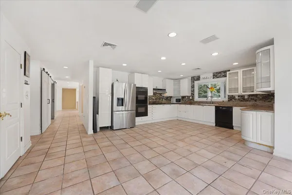 a view of kitchen with white cabinets stainless steel appliances and a center island