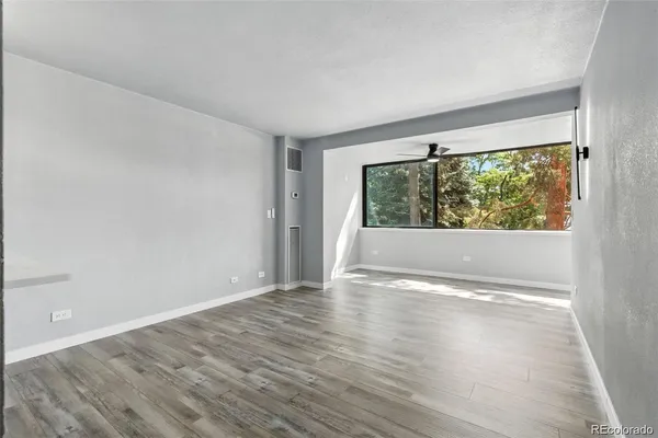 a view of an empty room with wooden floor and a window