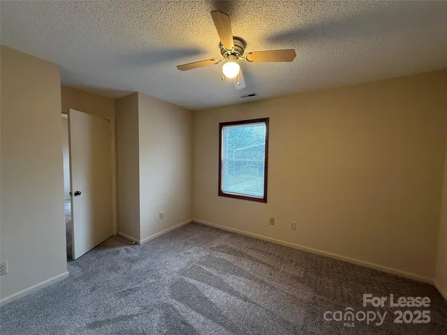 an empty room with a ceiling fan and a window