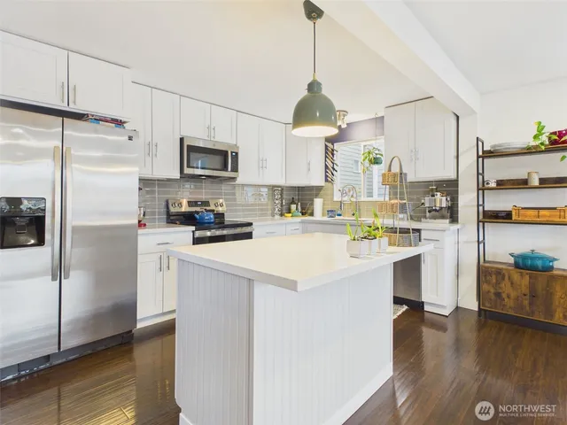 a kitchen with stainless steel appliances a stove top oven a sink cabinets and wooden floor
