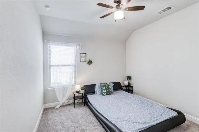 a bedroom with a large bed a flat tv screen and a dresser