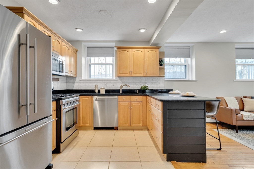 60 Charlesgate West, Unit BA Boston, MA 02215 - Photo 14 of 37 a kitchen with granite countertop wooden cabinets a stove a sink and a window