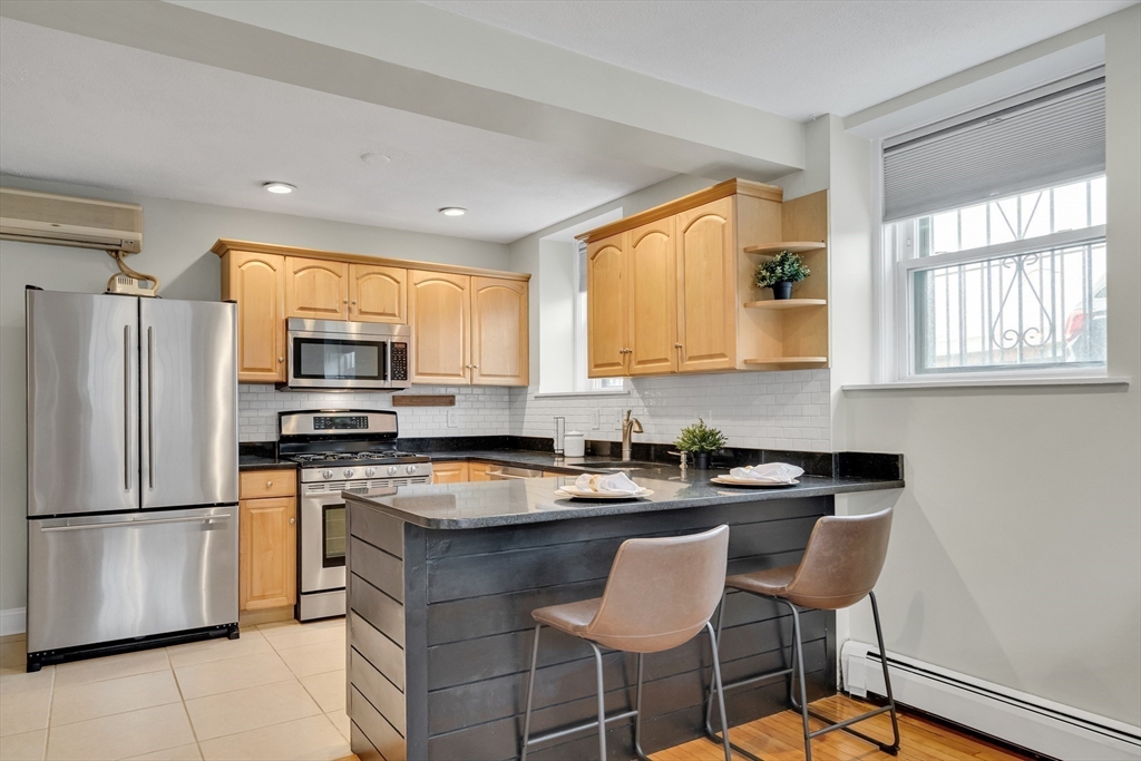 60 Charlesgate West, Unit BA Boston, MA 02215 - Photo 16 of 37 a kitchen with stainless steel appliances granite countertop a stove a sink a refrigerator a dining table and chairs
