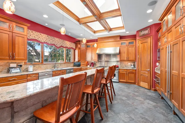 a dining hall with stainless steel appliances kitchen island granite countertop a table and chairs