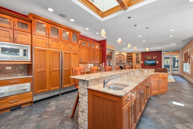 a kitchen with kitchen island granite countertop a sink and a refrigerator