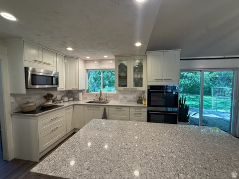 340 Willow Ridge Circle Centerville, UT 84014 - Photo 7 of 32 Kitchen featuring light-toned cabinetry, stainless steel appliances, a tile backsplash, recessed lighting, and a spacious island with a speckled countertop