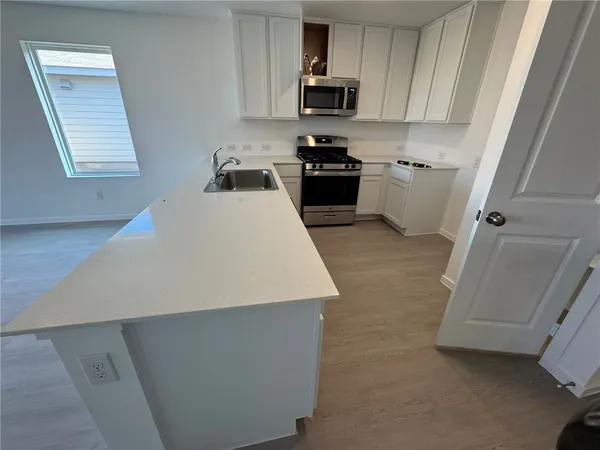 a large white kitchen with sink stainless steel appliances and cabinets