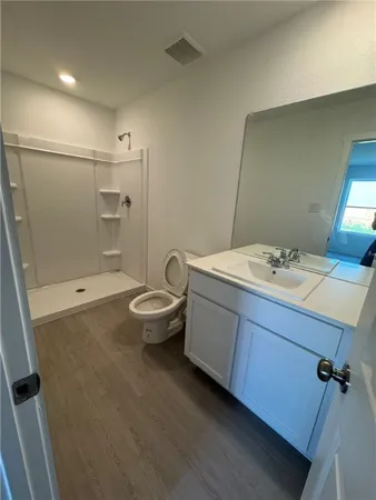 a bathroom with a granite countertop sink a toilet and shower