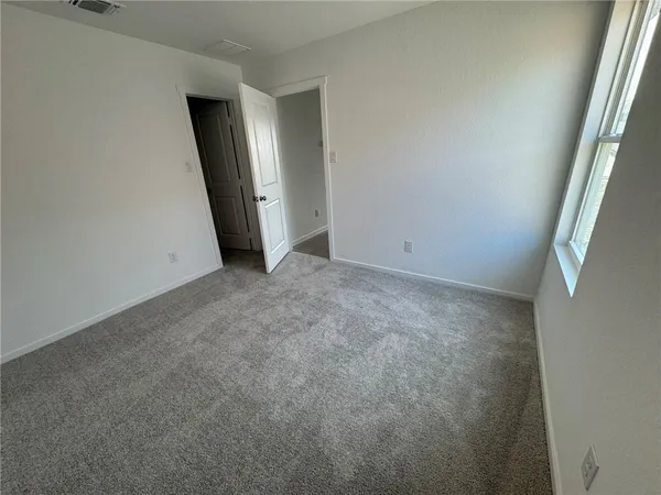 an empty room with window and a refrigerator