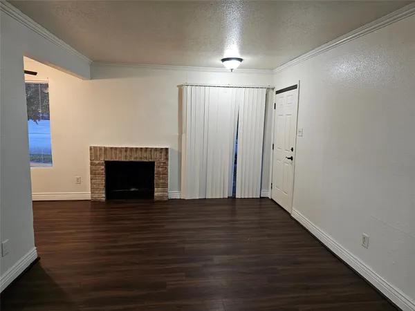 a view of an empty room with wooden floor and a fireplace