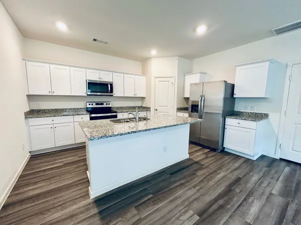 a kitchen with stainless steel appliances a refrigerator sink and white cabinets