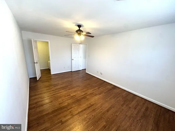 an empty room with wooden floor and chandelier fan